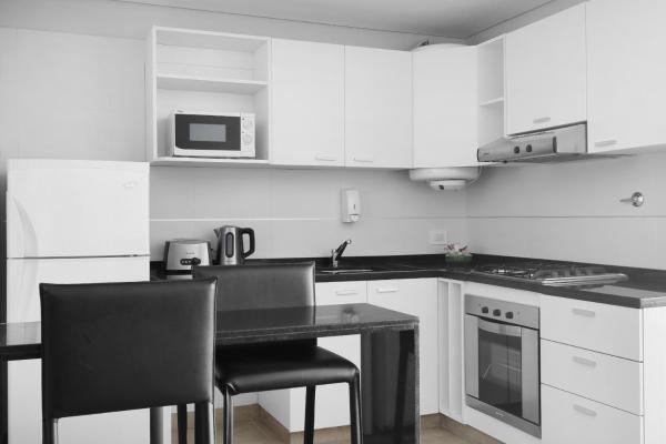 una cocina con armarios blancos, mesa negra y sillas en Excelente departamento ubicado en una zona privilegiada de Recoleta en Buenos Aires