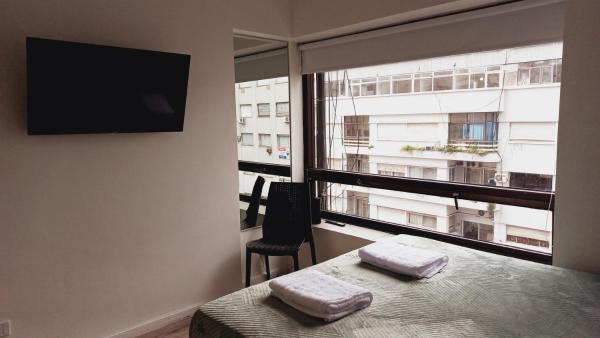 1 dormitorio con 1 cama y ventana con TV en Green Studio en Buenos Aires