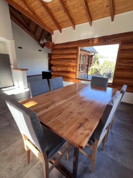 una mesa de madera y sillas en la sala de estar. en Villa Soñada - Encantadora Casa para 6 Personas en Esquel