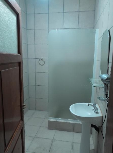 y baño blanco con lavabo y ducha. en departamento Gorriti en San Salvador de Jujuy