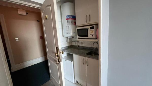 una pequeña cocina con armarios blancos y microondas en Apartments Millennium InnMendoza en Mendoza