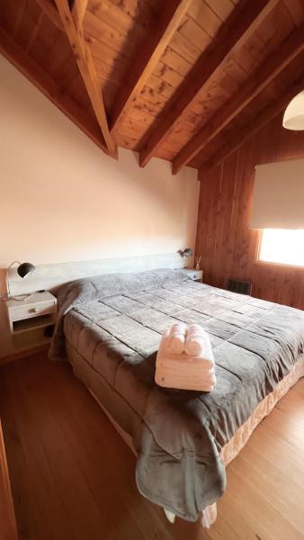 1 dormitorio con 1 cama en una habitación con techos de madera en El Abedul Cabaña en La Cascada, SMA en San Martín de los Andes