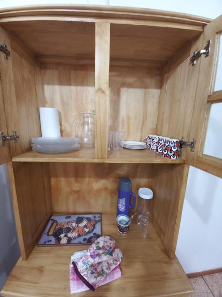 un armario de madera con una estantería con platos y una bebida en HOSPEDAJE SENDEROS CATARATAS en Puerto Iguazú