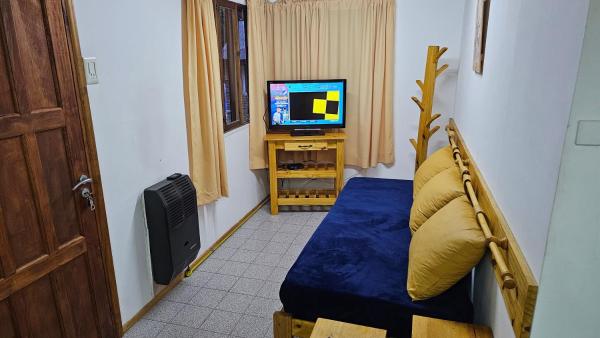 Habitación pequeña con cama y TV. en Valhalla Casita centrica en San Martín de los Andes
