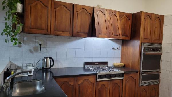 cocina con armarios de madera y horno con fogones en Casa céntrica en Salta