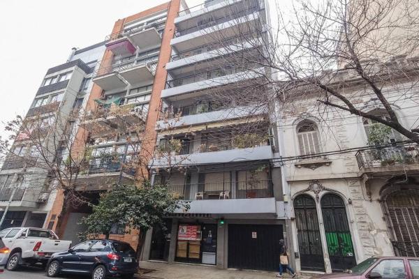 un edificio alto con coches estacionados frente a él en Departamento 3 Ambientes con terraza colegiales en Buenos Aires