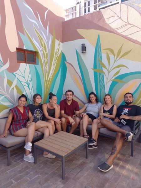 un grupo de personas sentadas en un sofá frente a un mural en Bitelyus Hostel Club en Mar del Plata