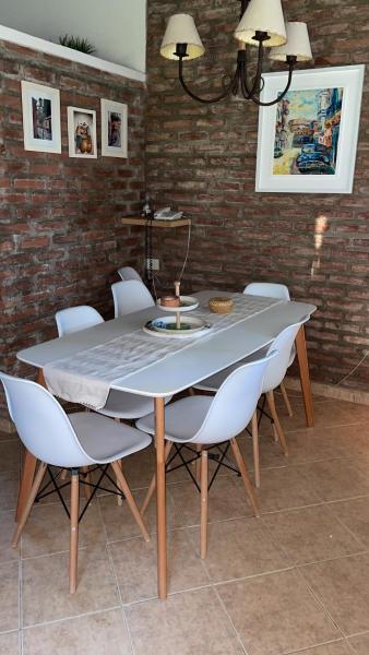 comedor con mesa y sillas blancas en Villa emma en Villa General Belgrano