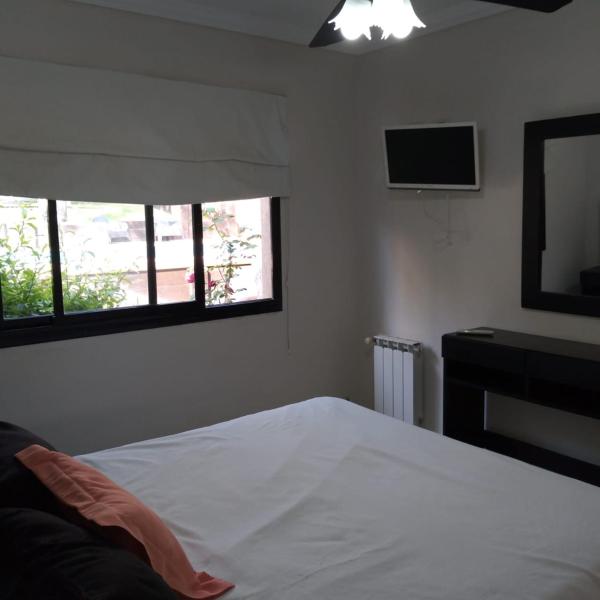 1 dormitorio con 1 cama y TV en la pared en Complejo Azul Marino en Villa Gesell