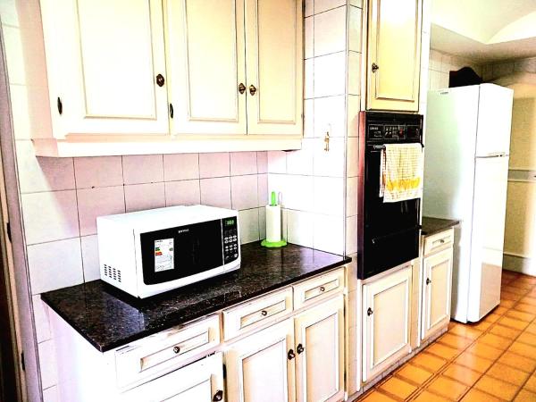 cocina con armarios blancos y microondas blanco en Casa Bravo en Mendoza