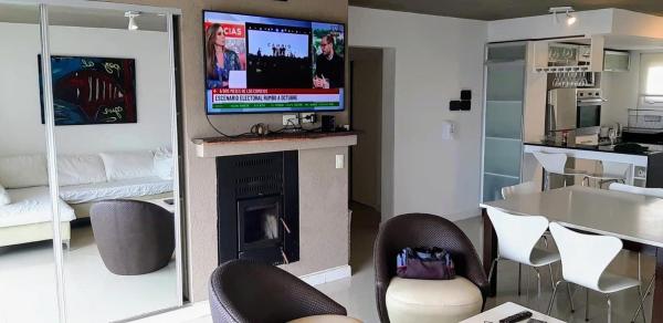 sala de estar con chimenea y TV en la pared en Linda Bay 223, Mar de las Pampas en Mar de las Pampas