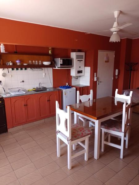 una cocina con mesa de madera y sillas y una cocina con paredes rojas. en Espacio 20 de febrero en Salta