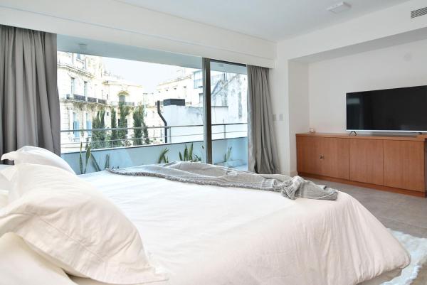 1 dormitorio con cama blanca y ventana grande en Esmeralda 1061-204 en Buenos Aires