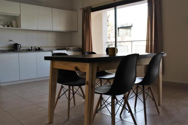 cocina con mesa de madera y sillas negras en Chañares Centric Apartment en Mendoza
