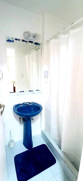 y baño con lavabo azul y ducha. en Amar el mar en Puerto Madryn