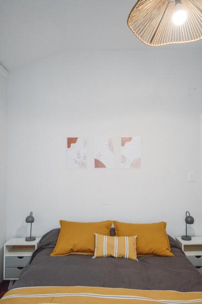 1 dormitorio con cama y pared blanca en Anden Aristides en Mendoza