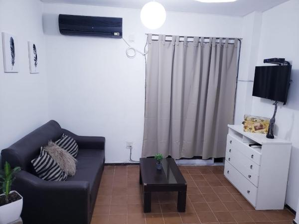 sala de estar con sofá negro y TV en Departamento en capital Mendoza con estacionamiento incluido en Mendoza