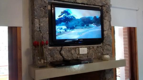 TV en una pared de piedra en una habitación en Escondida en el Bosque en Mar de las Pampas