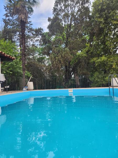una piscina azul con una valla y árboles en LOS OLIVARES. SAN LORENZO en Salta