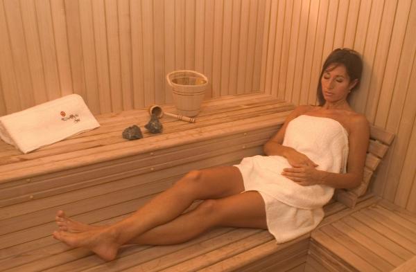 una mujer sentada en una sauna con una toalla en Pillmayken Apart&Spa Mar de las Pampas en Mar de las Pampas