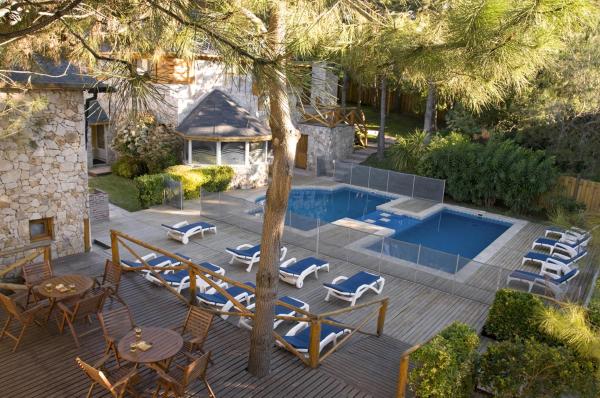 una terraza con sillas, una piscina y una casa en Pillmayken Apart&Spa Mar de las Pampas en Mar de las Pampas