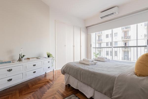 Dormitorio blanco con cama y ventana grande en Fliphaus Cordoba 2500 - 3 Bd Facultad Medicina en Buenos Aires
