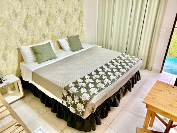 1 dormitorio con 1 cama grande con almohadas verdes en Tupa hotel iguazu en Puerto Iguazú