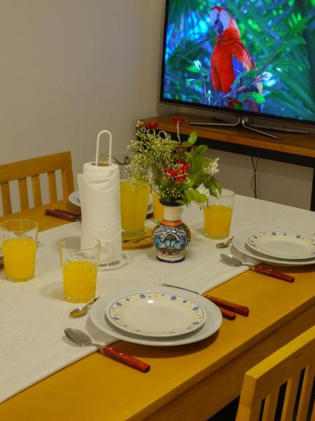 una mesa con platos y gafas y un pájaro rojo en la TV en Departamento en Edificio Torre Eiffel en Mar del Plata