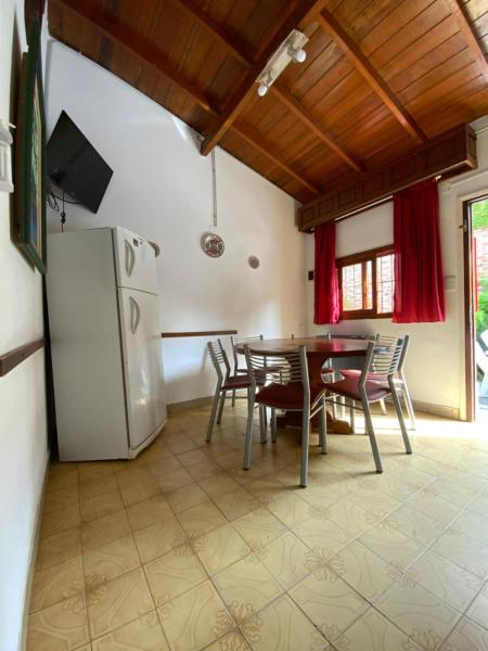 cocina con mesa, sillas y heladera en Complex Quimey alojamiento familiar en Villa Gesell