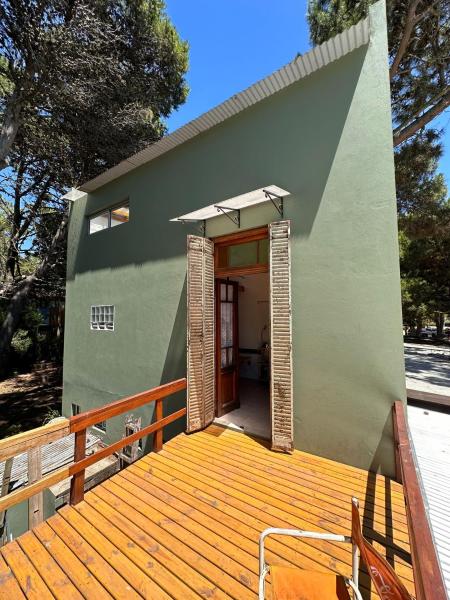 una pequeña casa verde con terraza de madera en Plumerillos aparte en Mar de las Pampas