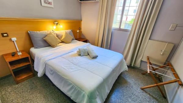 Un dormitorio con una gran cama blanca y una ventana en Hotel Juan B Justo en Mendoza