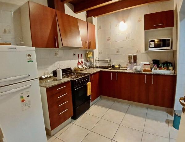 cocina con armarios de madera y refrigerador blanca en "Tu refugio espacioso en el corazón de MENDOZA" en Mendoza