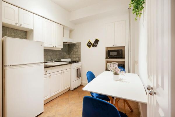 cocina con nevera blanca y mesa con sillas azules en 61-2A Large 1BR in Upper East Side, en Nueva York