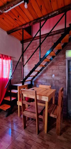 una mesa de madera y bancos en una habitación con escaleras en HOSPEDAJE DODERA en Gualeguaychú