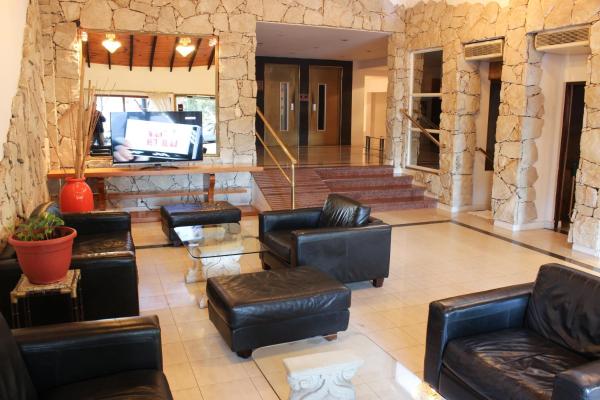sala de estar con muebles de cuero y TV en Hotel Arenas en Pinamar
