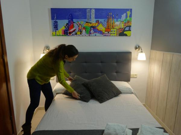 una mujer parada en la parte superior de una cama en Hostal Lleida, en Barcelona