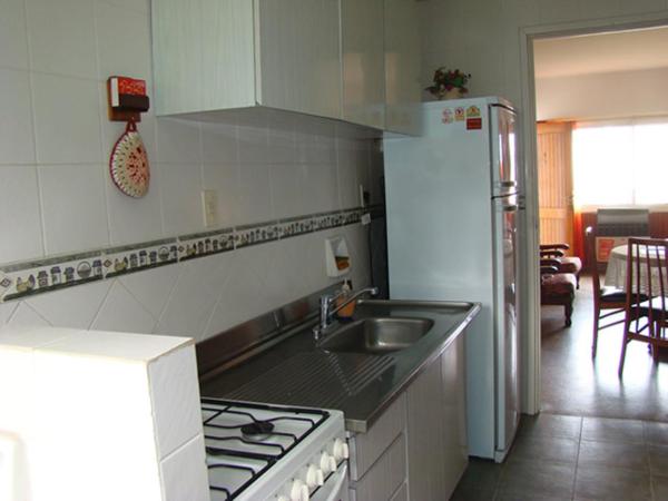 una cocina con fregadero y fogones y nevera en YAI Departamentos en Villa Gesell