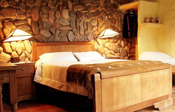 1 dormitorio con cama y pared de piedra en Rincon del Valle en San Salvador de Jujuy