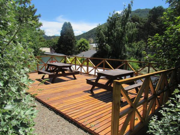una terraza de madera con 2 mesas de picnic. en Apart Cascadas en San Martín de los Andes