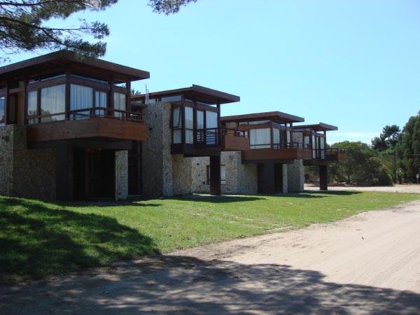 un edificio con balcones junto a un campo en Cabañas Arenas Blandas en Villa Gesell
