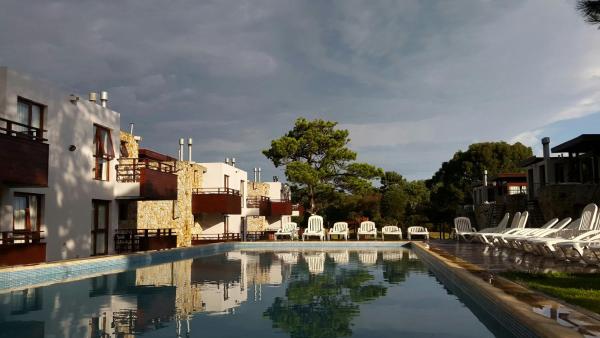 una piscina con sillas blancas y un edificio en Cabañas Arenas Blandas en Villa Gesell