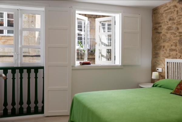 un dormitorio con una cama verde y dos ventanas en la Pensión Rúa Nueva de Santiago de Compostela
