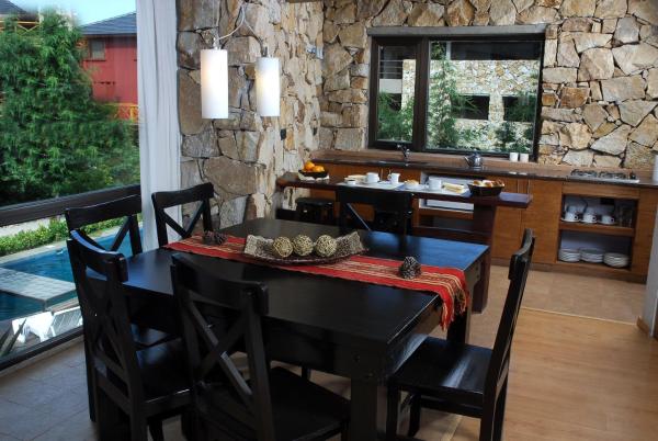 comedor con mesa y pared de piedra en Village de las Pampas Apart Hotel Boutique, en Mar de las Pampas