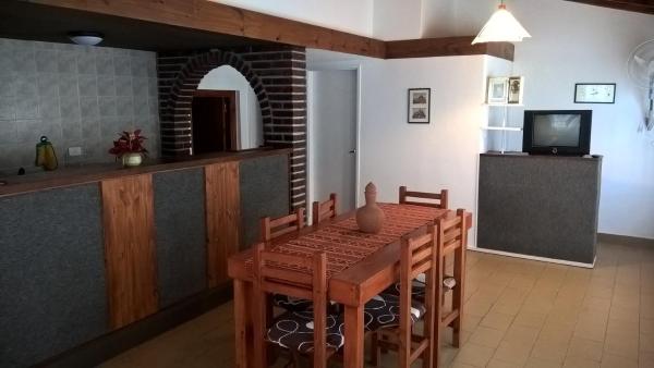 cocina y comedor con mesa y TV en Playa 1 en Villa Gesell