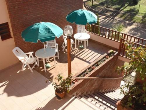 un balcón con dos mesas y sillas y sombrillas en el Aparte Familiar Antu Alen I en Villa Gesell