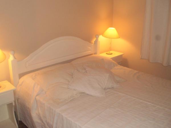 1 cama blanca en un dormitorio con 2 lámparas en el Departamento a media cuadra del mar Edificio "Mont Blanc" en Villa Gesell