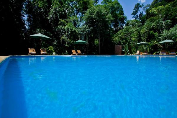 una gran piscina azul con sillas y sombrillas en Tierra Guaraní Lodge en Puerto Iguazú