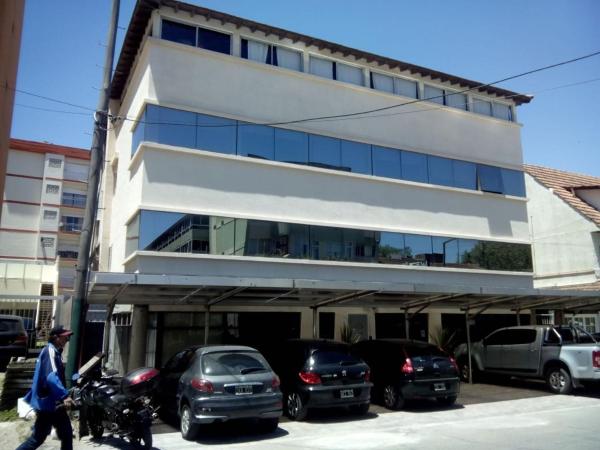 un edificio con coches estacionados en un estacionamiento en el Hotel Maracas en Villa Gesell