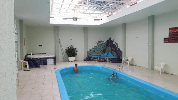 two people in a swimming pool in a building at Apto Ingleses à 50mts da praia in Florianópolis