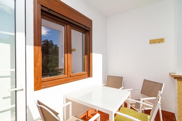 una mesa y sillas blancas en una habitación con ventana en Los Flamencos Malaga Casasol, en Málaga